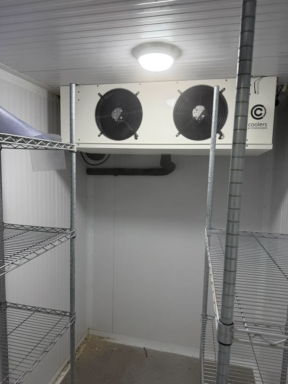 Interior of a walk-in cold room with evaporator fans and shelving